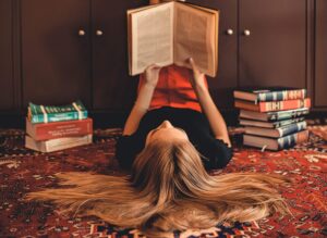 woman-lying-on-area-rug-reading-books-2899918