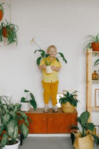 boy-in-yellow-jacket-and-pants-standing-beside-green-plants-3771666