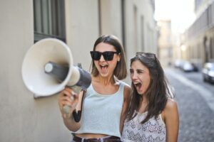 cheerful-young-women-screaming-into-loudspeaker-3764551