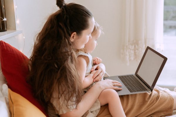 mother-embracing-daughter-while-surfing-internet-on-laptop-3975663