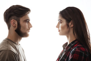 Side view. Closep portrait of man and woman facing each other with eyes open.