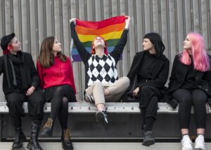 non-binary-friends-sitting-holding-lgbt-flag