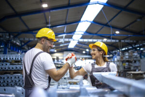 Factory workers handshaking each other at production line.