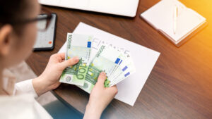 Woman working with finances counting money on the table. Smertphone, notepad