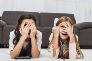 young-girl-covering-face-peeking-through-fingers-while-watching-television-home