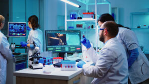 Microbiologist doctor taking a blood sample tube from rack with machines of analysis in the lab background. Doctors examining vaccine evolution using high tech researching diagnosis against covid19