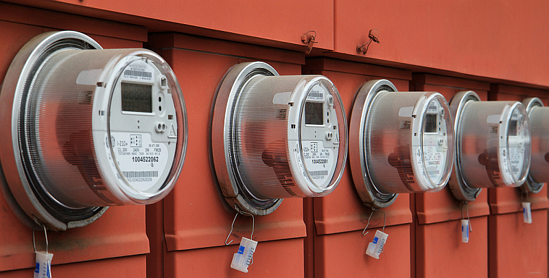 Line up of five elecric power meters on red electrical panels