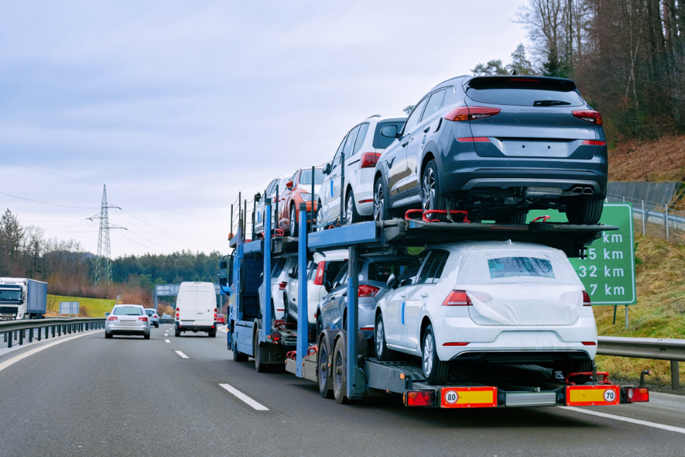 Car carrier transporter truck on road. Auto vehicles hauler on driveway. European transport logistics at haulage work transportation. Heavy haul trailer with driver on highway.