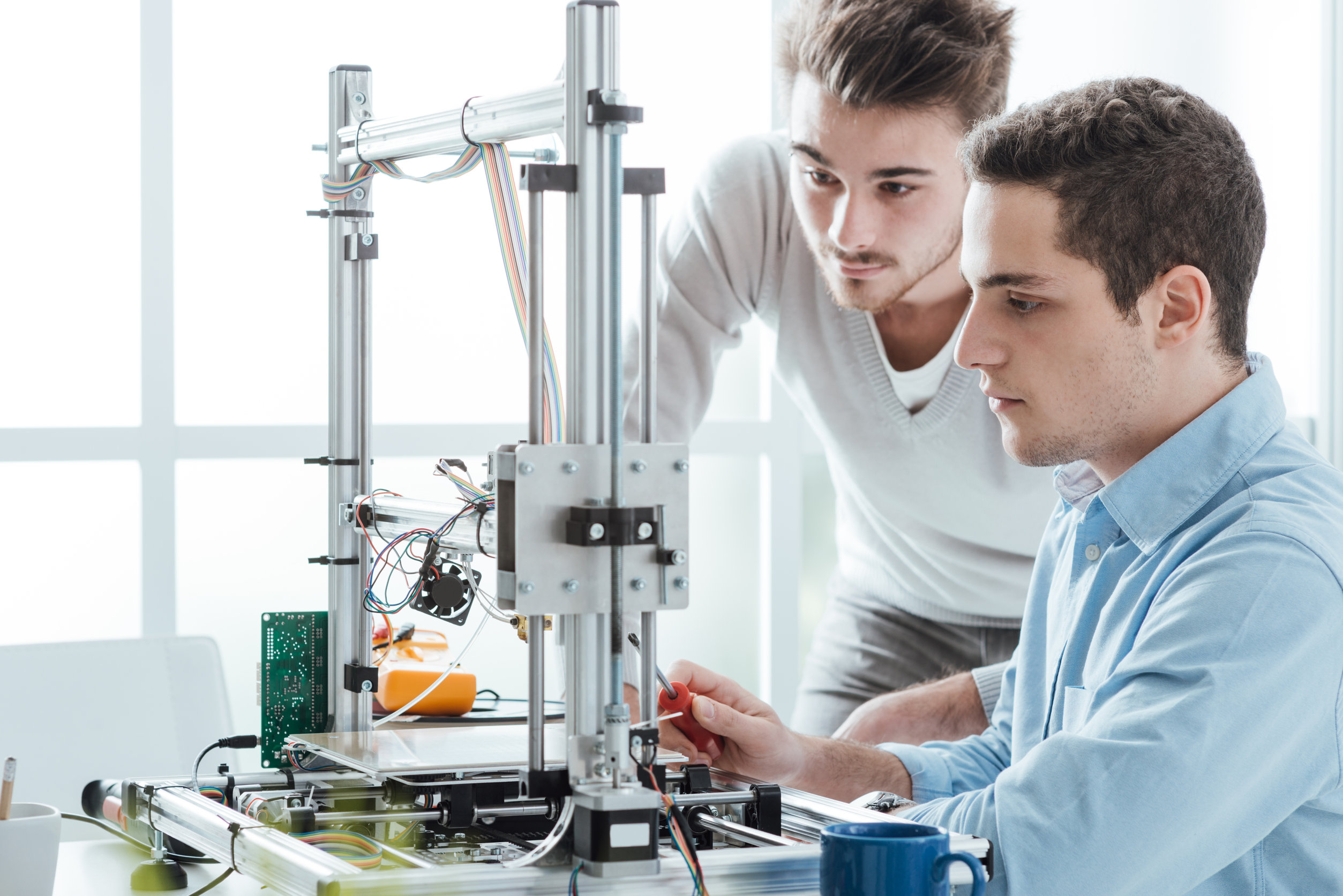 Young students in the laboratory using a 3D printer, technology and education concept