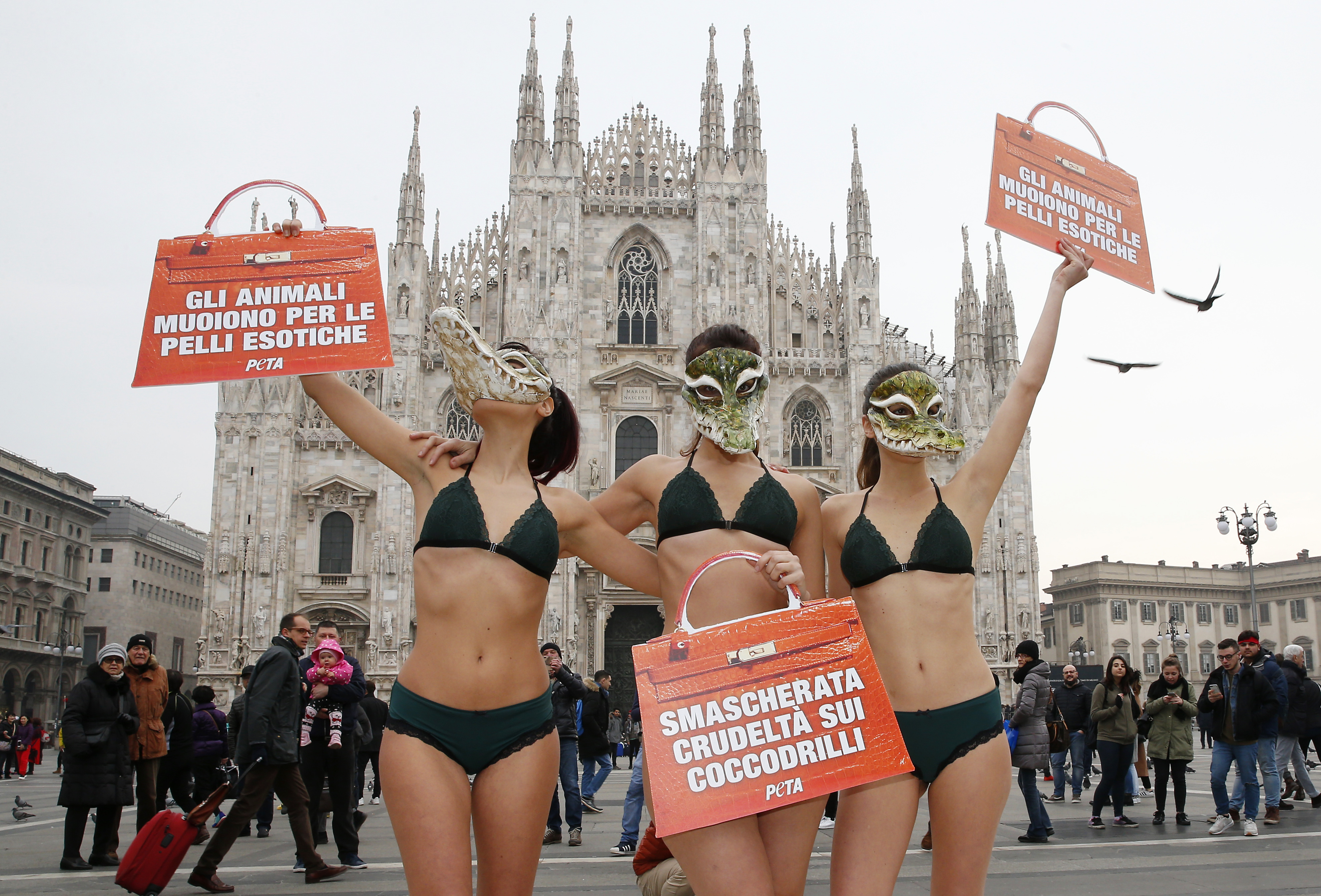 PETA (People for the Ethical Treatment of Animals) activists wear crocodile masks and hold up bag-shaped cards with writing reading in Italian "Animals die for exotic skins" and "Uncovered cruelty on crocodiles", during a demonstration against the use of crocodile skins ahead of Milan's Fashion Week, in Milan's Duomo Square, Italy, Tuesday, Feb. 21, 2017. Milan Fashion Week opens Wednesday. (AP Photo/Antonio Calanni)
