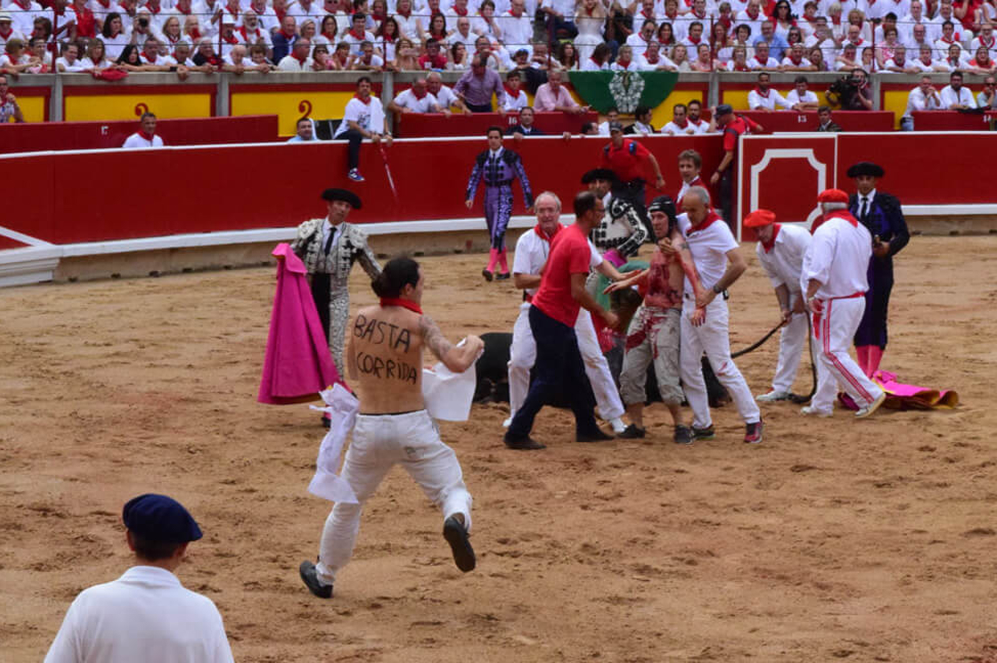 Animal activists invade a bullring, with man centre left displaying the legend "Just run" written on his back, attempting to intervene in the killing of a bull at this year's San Fermin festival and seeming to comfort the fatally wounded bull, in Pamplona, Spain, Thursday July 6, 2017. According to PETA (People for the Ethical Treatment of Animals) their protest aims to raise awareness about what they say is the "cruel and barbaric" way the animals are killed. (PETA/Vegan Strike Group via AP)