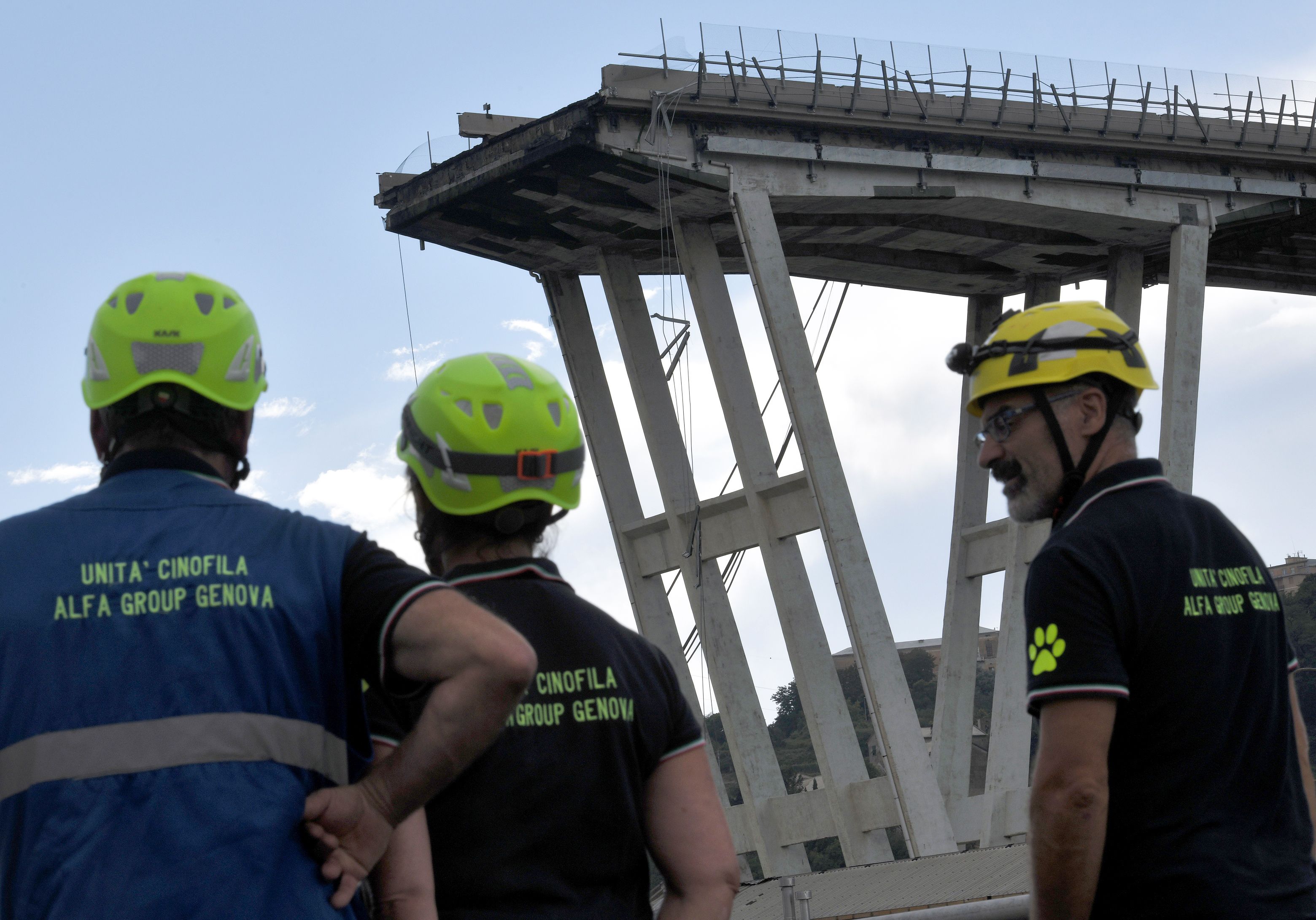 Rescuer look towards the Morandi motorway bridge after a section of the bridge collapsed earlier in Genoa on August 14, 2018. - At least 30 people were killed on August 14 when the giant motorway bridge collapsed in Genoa in northwestern Italy. The collapse, which saw a vast stretch of the A10 freeway tumble on to railway lines in the northern port city, was the deadliest bridge failure in Italy for years, and the country's deputy transport minister warned the death toll could climb further. (Photo by PIERO CRUCIATTI / AFP)