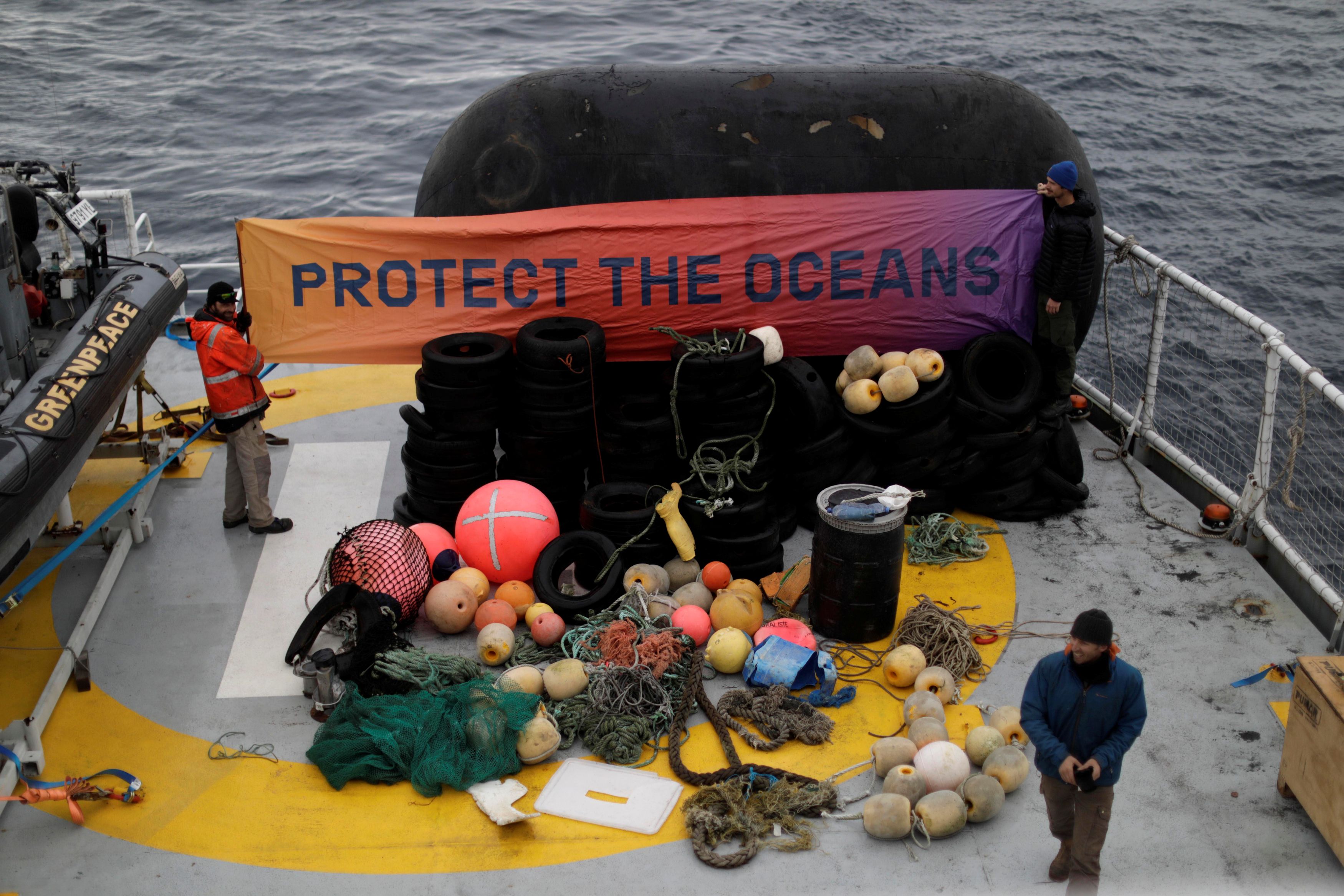 Climate change activists from Greenpeace, hold up a sign reading 'protect the oceans', in front of rubbish collected from the islands of Antarctica, on the Esperanza Ship, close to Orne Harbor, Antarctica, February 6, 2020. Picture taken February 6, 2020. Reuters/Ueslei Marcelino